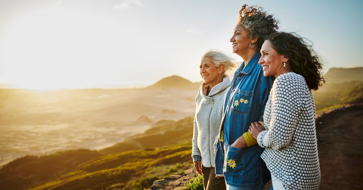 Three older women standing at the top a mountain looking at the horizon