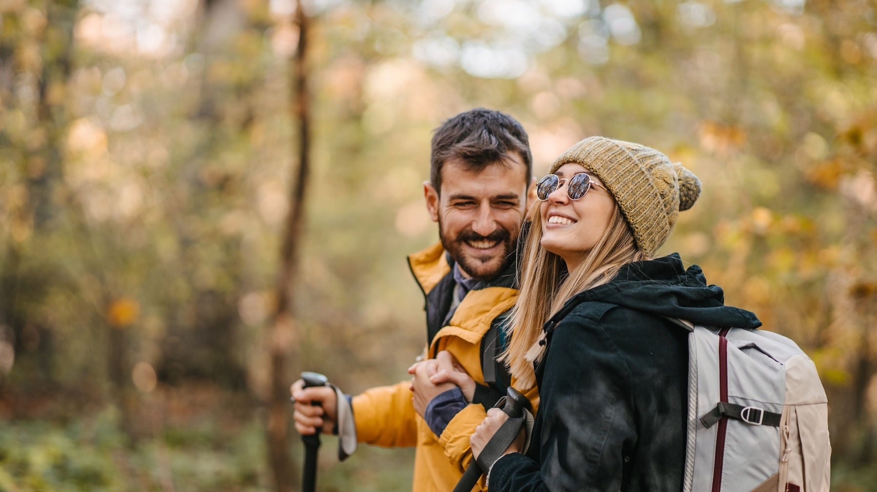 Young couple hiking. Hugging and smiling while walking and having a good time together