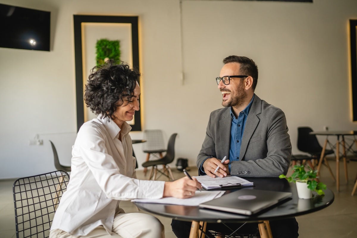 Mature woman sign insurance or contract to adult man in cafe
