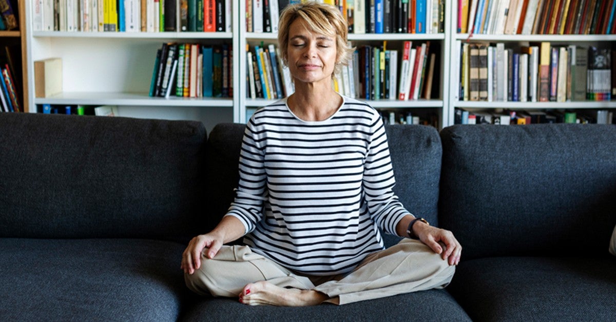 A women meditating on a couch.
