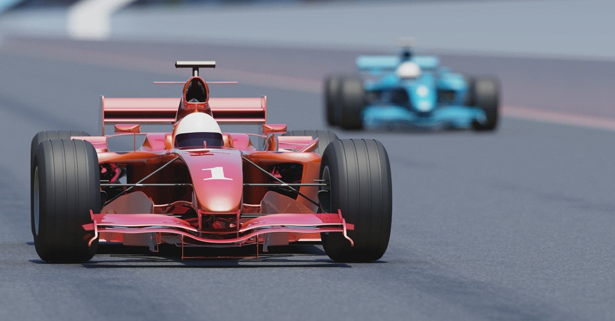 racecars zooming on speedway track