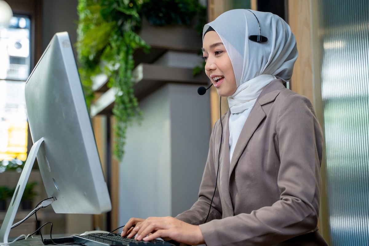 Friendly operator woman agent with headsets working in a call centre,Smiling support phone operator woman wearing Hijab working in customer service.