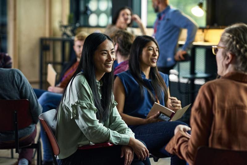 Upward view of modern skyscrapers and the CN Tower against a colorful sunset sky with soft pink and blue clouds.