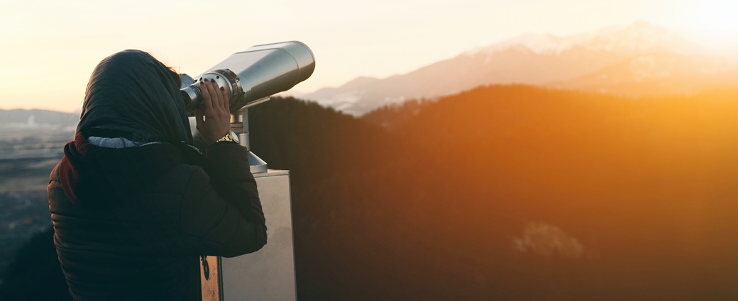 Rear view of person using binoculars to view scenery