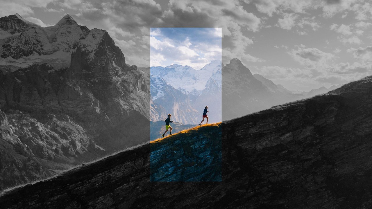 two people hiking up an incline with mountains in the background