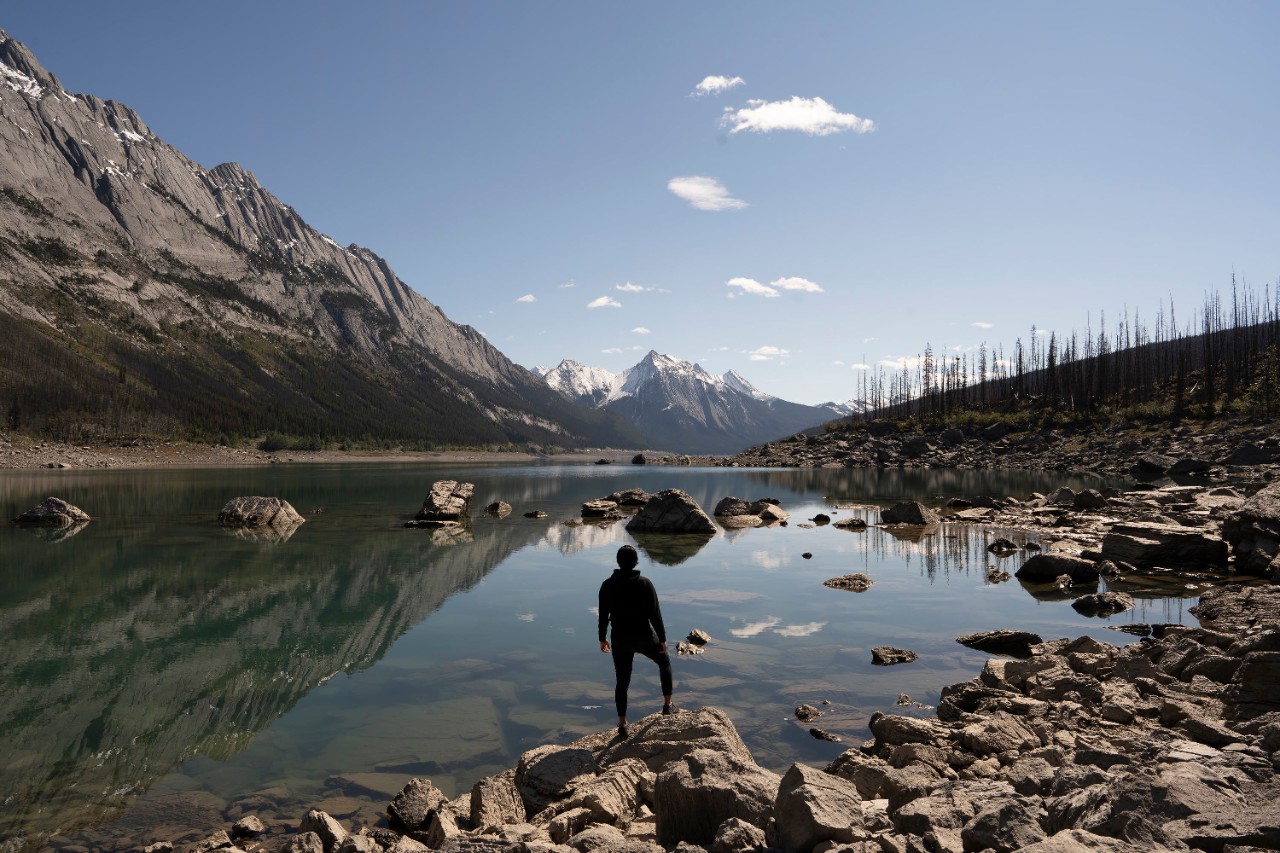 Man looking at mountains in Medicine Lake, Canada