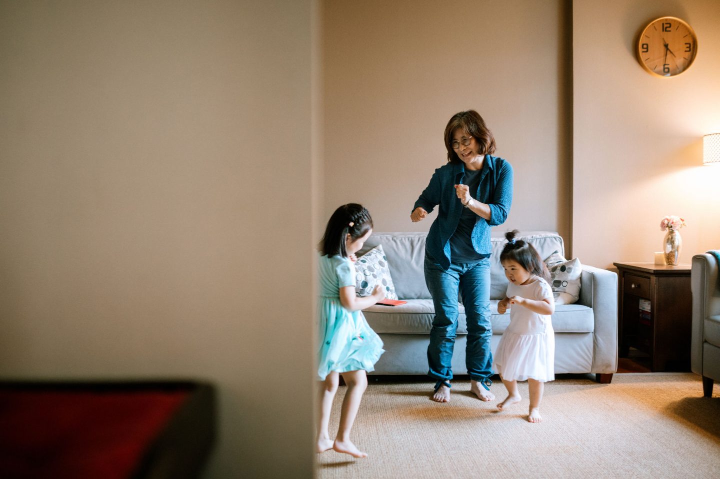 A loving Korean family dances together in the living room, enjoying spending time together again.  The grandma teaches her granddaughters fun dances and games.